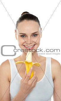 Cheerful fit woman eating banana