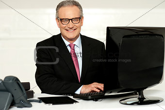 Happy aged corporate man typing on keyboard