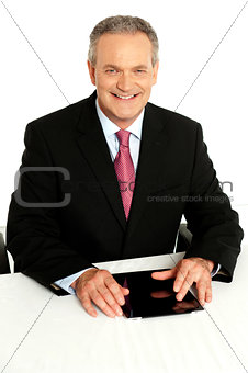 Senior businessman sitting with tablet on desk