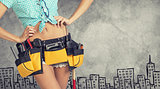 Woman in tool belt, hands on hips. Cropped image. Sketch buildings as backdrop 