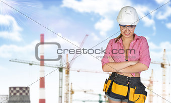 Woman in tool belt and helmet. Tower cranes, chimneys as backdrop
