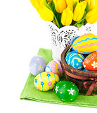 Easter eggs in basket with yellow tulips