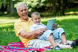 grandfather and child in park using tablet