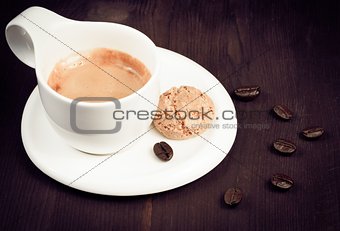 cup of espresso coffee and biscuit near coffee beans, old style