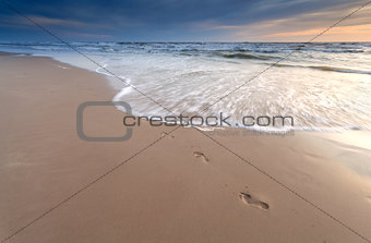 foot prints on sand beach at sunset