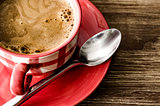 Detail of coffee in red cup on wooden vintage table