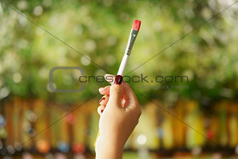 Young female painter holding painting brush at canvas