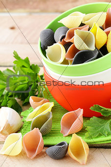 uncooked tricolor pasta in bowl on a wooden table