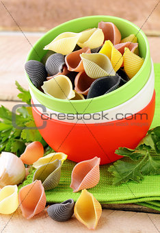 uncooked tricolor pasta in bowl on a wooden table