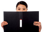 Chinese woman hiding face with business file