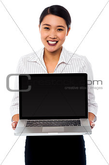 Smiling saleswoman presenting brand new laptop