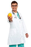 Happy young doctor offering you orange