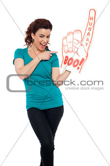 Young woman pointing at large foam hand