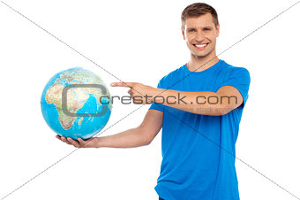 Handsome young caucasian pointing at globe