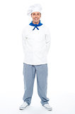 Smart young smiling male chef posing casually