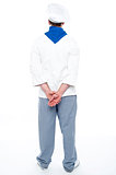 Rear view of male chef posing with hands behind