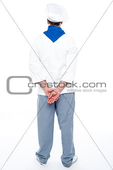 Rear view of male chef posing with hands behind