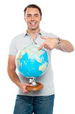 Isolated young man pointing at globe