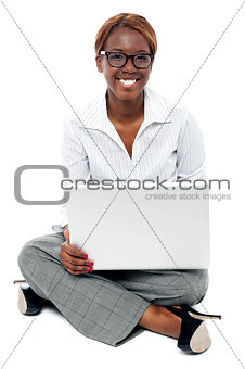 Corporate lady seated on floor working on laptop