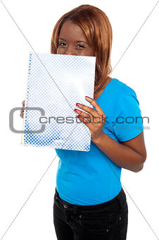 Pretty girl hiding her face through notebook