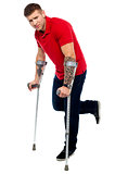 Painful expression of young guy walking with help of crutches
