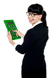 Bespectacled woman turning back, holding calculator