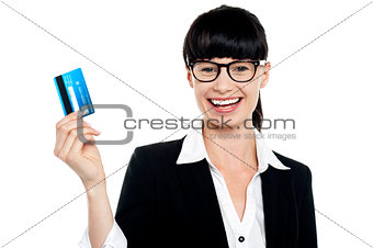 Cheerful bespectacled woman holding up her cash card