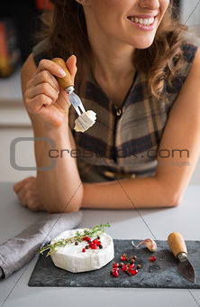 Closeup on happy young woman eating camembert