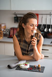 Young woman eating camembert in kitchen