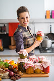 Portrait of happy young housewife with jars of pickled vegetable