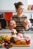 Happy young housewife with jars of pickled vegetables