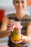 Closeup on young housewife showing jar with pickled vegetables