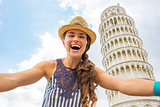 Portrait of young woman making selfie in front of leaning tower 