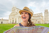 Smiling young woman with map on piazza dei miracoli, pisa, tusca