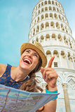 Young woman with map pointing in front of leaning tower of pisa,