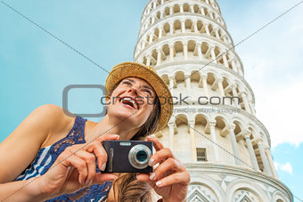 Happy young woman with photo camera in front of leaning tower of