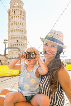 Happy mother and baby girl taking photo in front of leaning towe