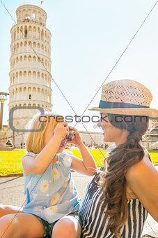 Baby girl taking photo of mother in front of leaning tower of pi