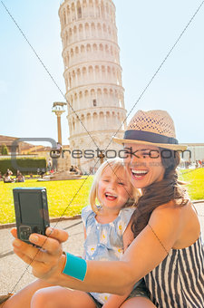 Happy mother and baby girl making selfie in front of leaning tow