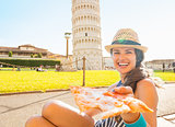 Young woman giving pizza in front of leaning tower of pisa, tusc