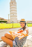 Closeup on young woman giving pizza in front of leaning tower of