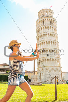 Funny young woman supporting leaning tower of pisa, tuscany, ita
