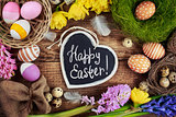 Black board with text - Happy Easter. Colorful Easter Eggs and flowers