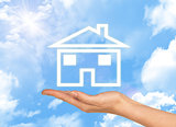 House icon on hand. Background of sky , clouds and sun
