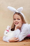 Happy girl in bunny costume holding her white rabbit