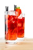 glasses of strawberry cocktail with ice on light wood table 