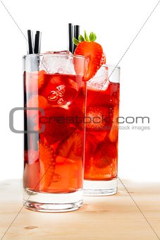 glasses of strawberry cocktail with ice on light wood table 