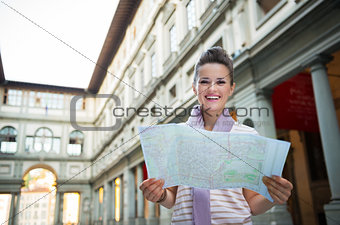 Portrait of happy young woman with map near uffizi gallery in fl