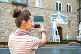 Closeup on young woman taking photo of palazzo vecchio in floren