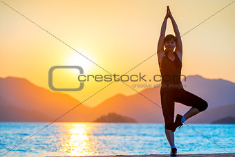 Pilates by the Sea. Girl balances at dawn